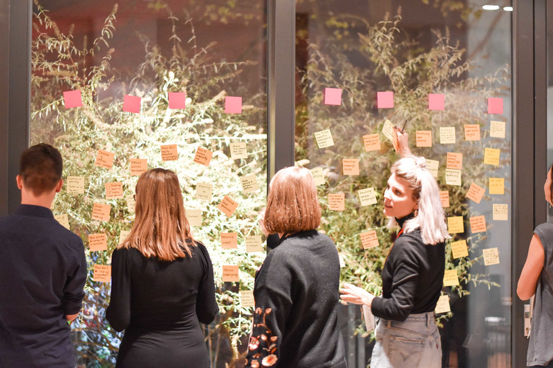 A group gather around post-it notes stuck to a large window